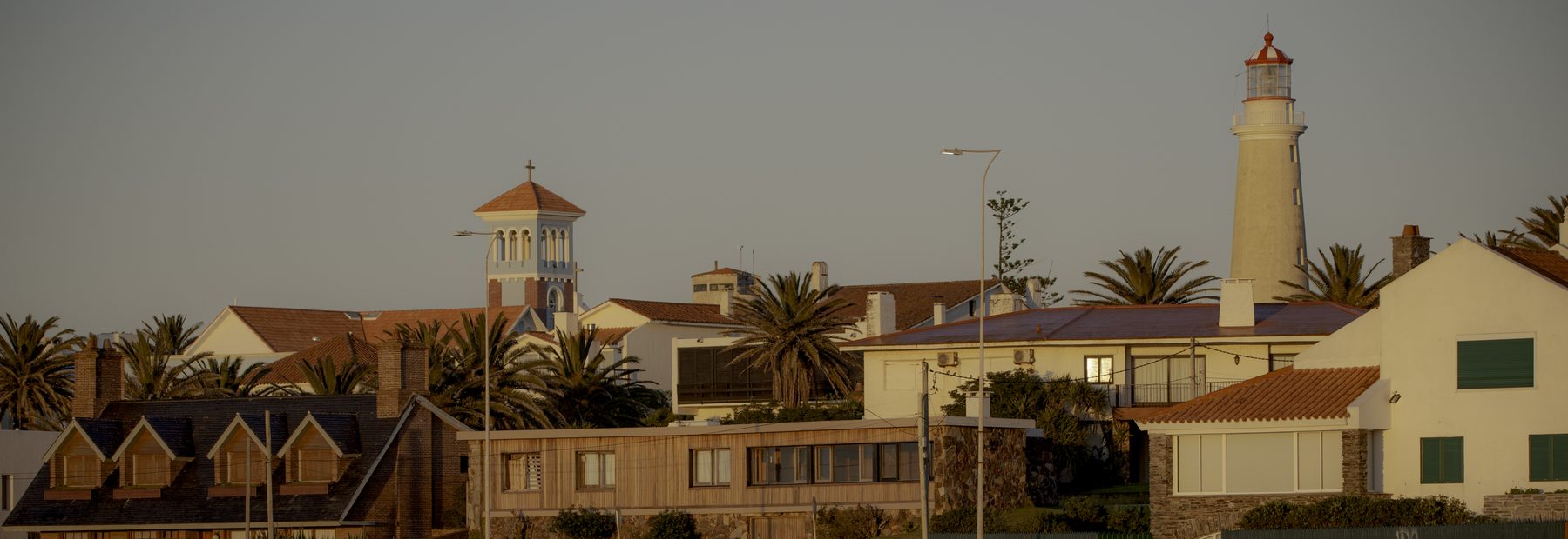 La península al atardecer: el faro y el campanario de la Candelaria sobre los techos del pueblo